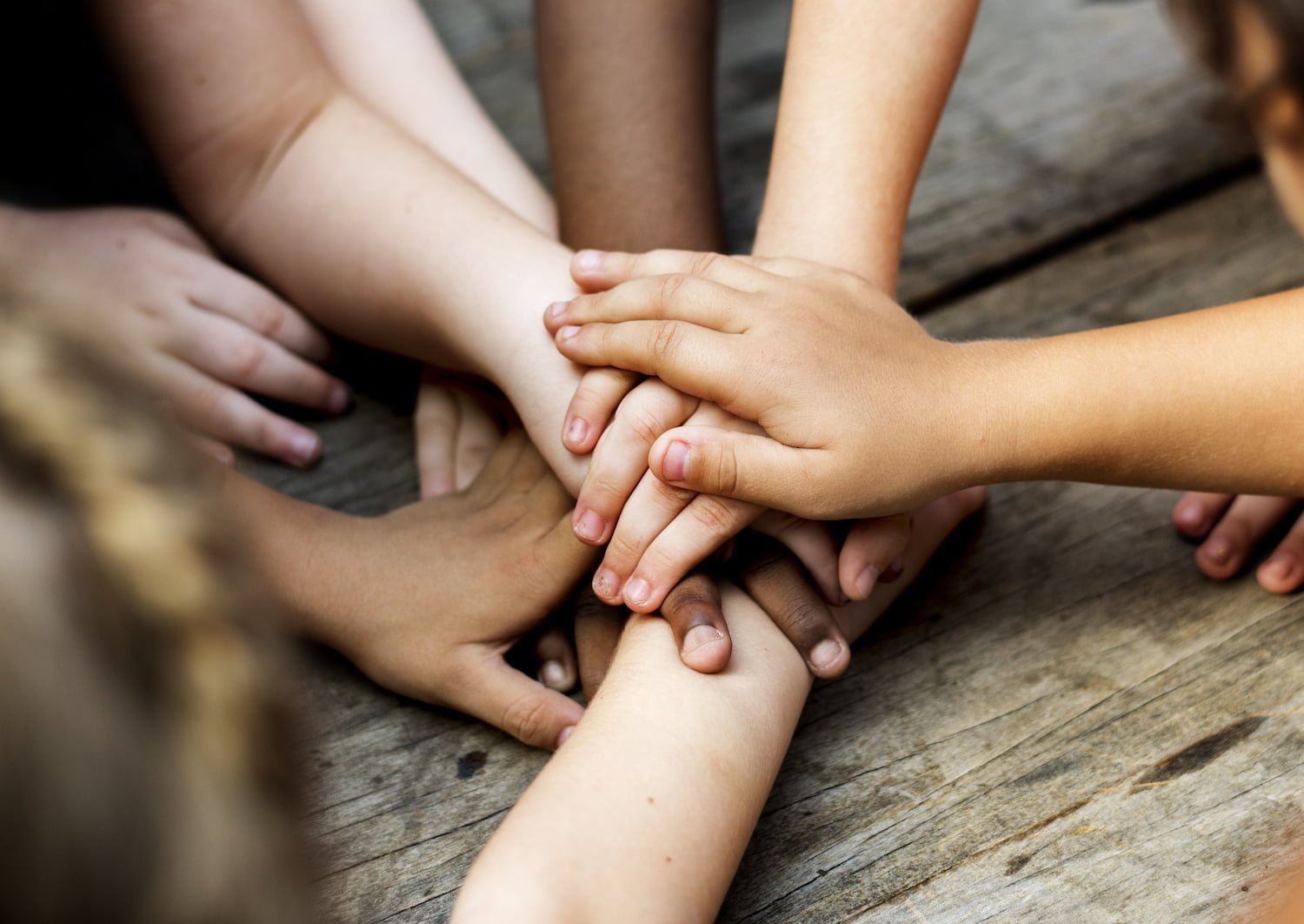 Diverse hands are join together on the wooden table